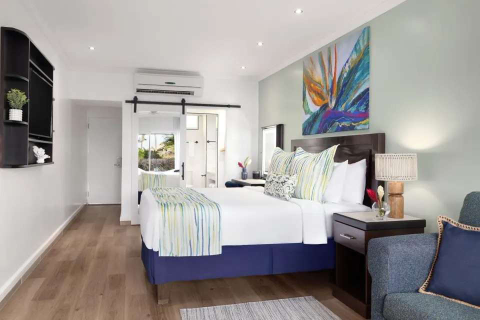 King bed, nightstand, and sliding bathroom door in a Harmony JR Suite at Coconut Bay Beach Resort & Spa.