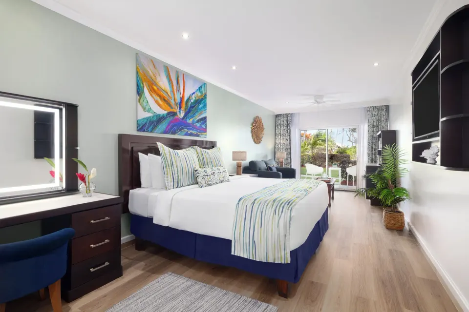 King bed, vanity, and lounge area in a Harmony JR Suite at Coconut Bay Beach Resort & Spa.
