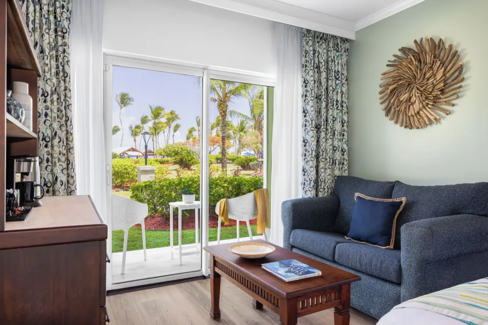 Blue sofa, coffee table, and patio doors in a Harmony JR Suite at Coconut Bay Beach Resort & Spa.