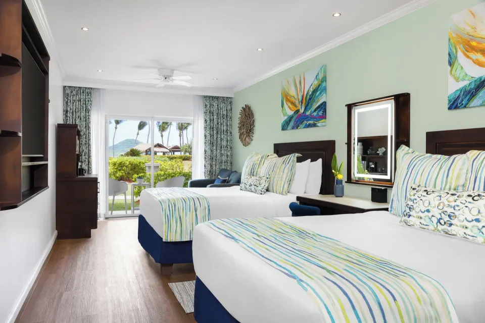 Two beds and patio view in a Harmony JR Suite Tropical View at Coconut Bay Beach Resort & Spa.