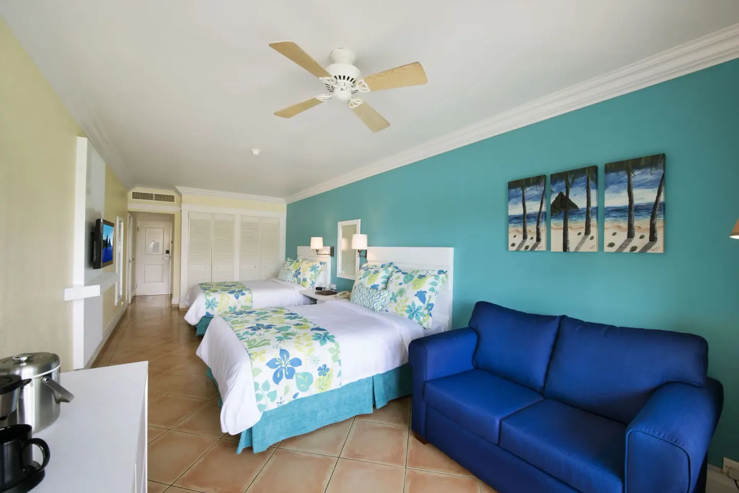 Splash Premium Oceanview room at Coconut Bay Beach Resort & Spa with two double beds and a blue sofa.