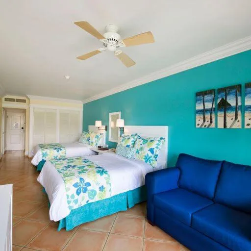 Two double beds and a blue sofa in a Splash Premium Oceanview room at Coconut Bay Beach Resort & Spa.