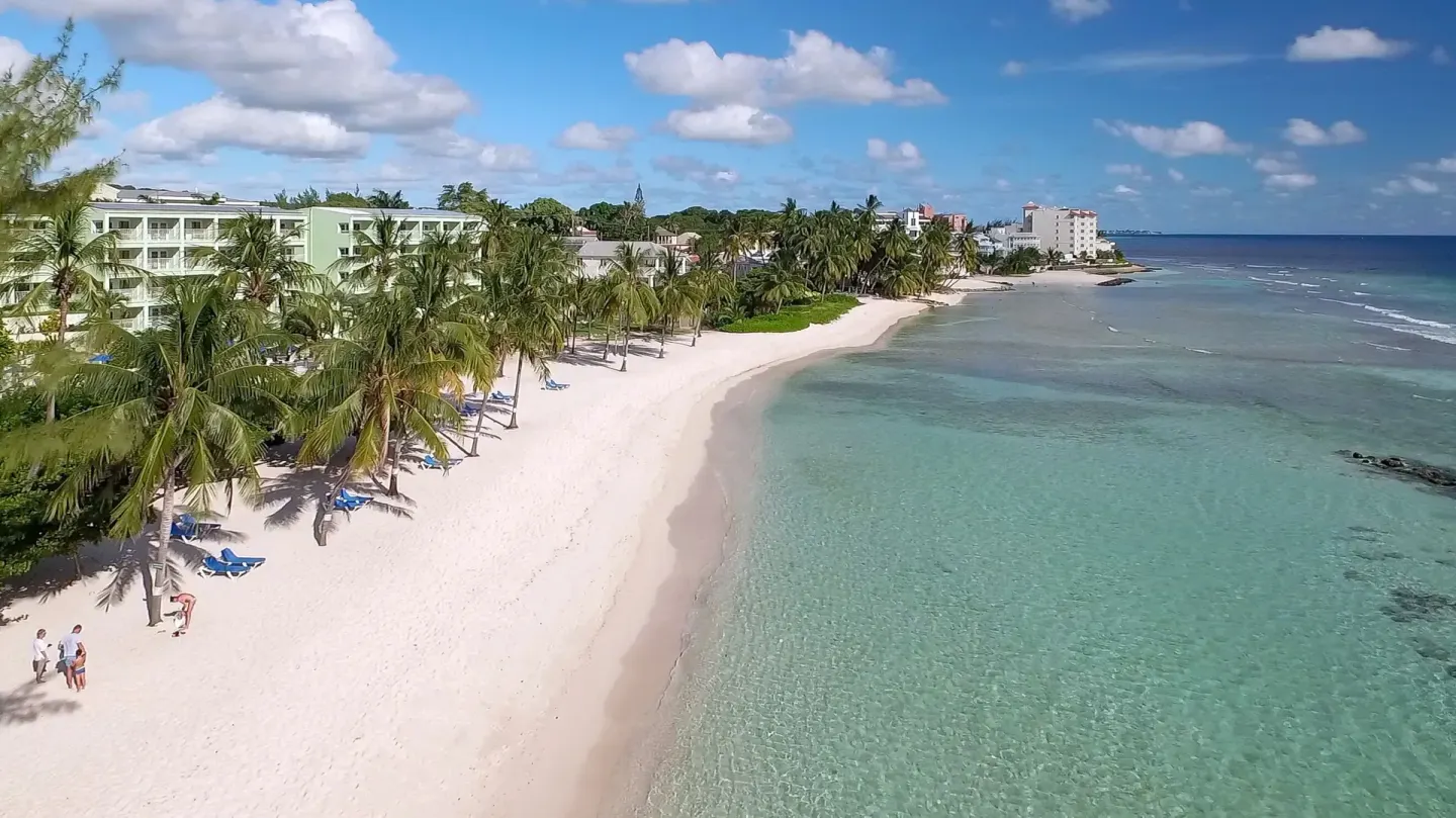 Aerial view of the beach, palms, and turquoise water at Coconut Court Beach Hotel.