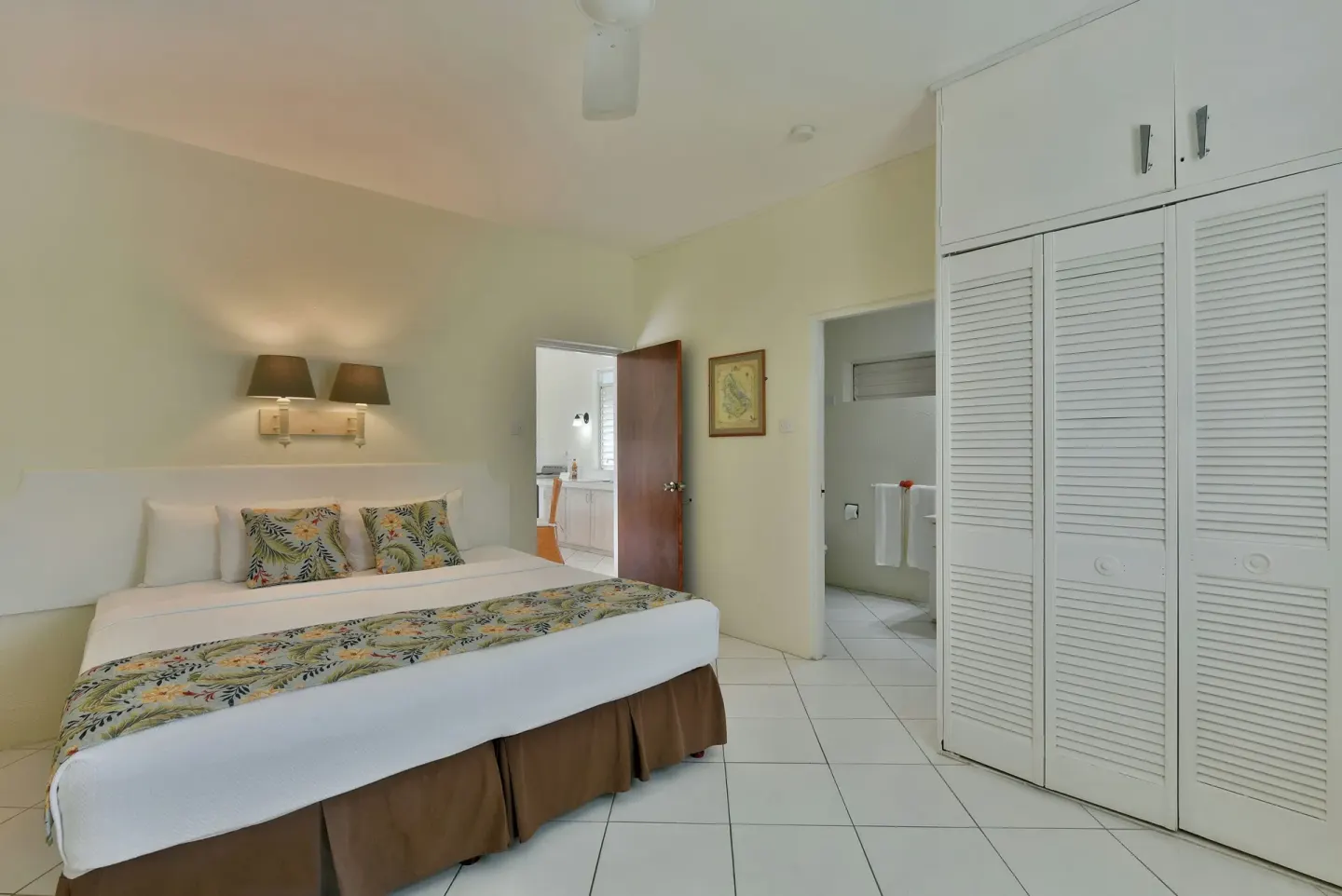 Guest room with king bed, closet doors, and bathroom entry at Coconut Court Beach Hotel.