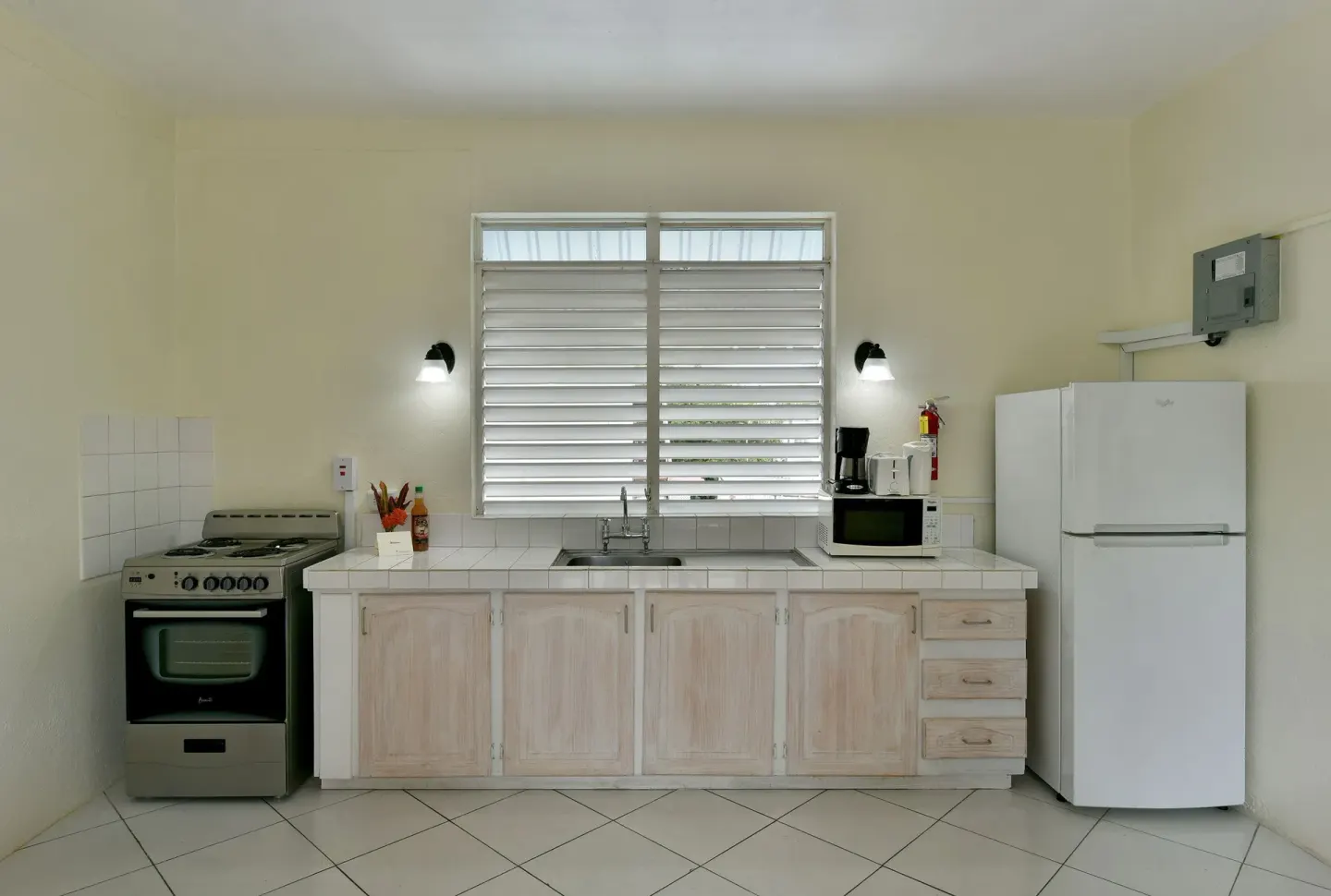 Guest room kitchen with stove, sink, refrigerator, and appliances at Coconut Court Beach Hotel.