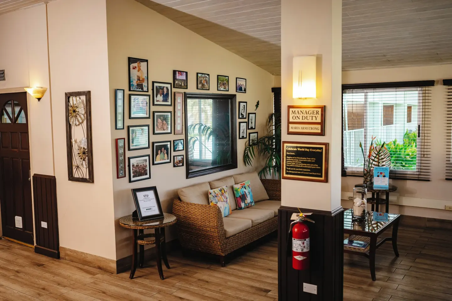 Lobby seating area with framed photos and windows at Coconut Court Beach Hotel.
