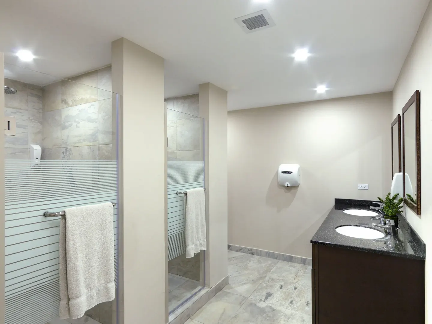 Modern bathroom with glass shower stalls and double sinks at Coconut Court Beach Hotel.