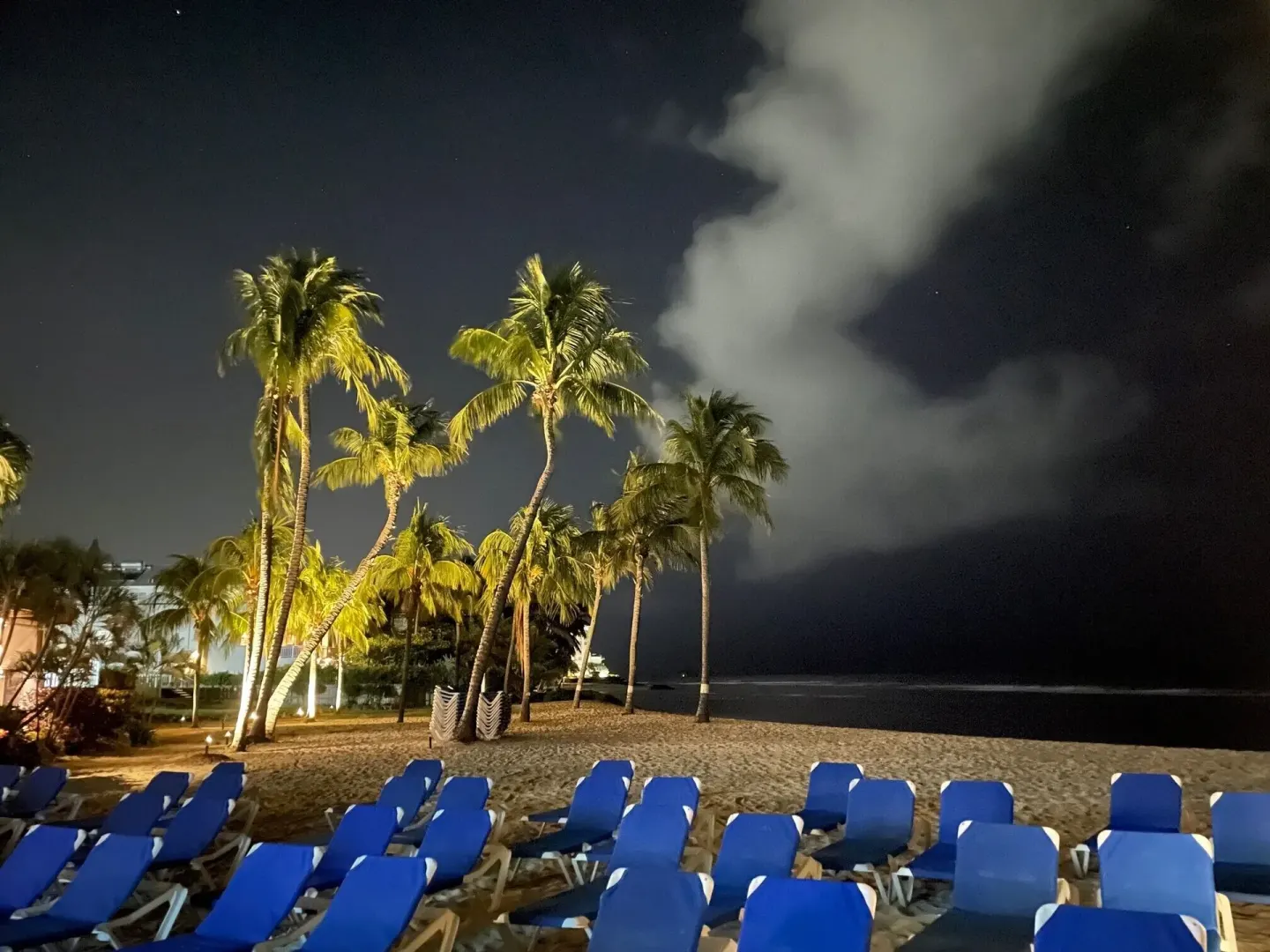 Blue loungers on the nighttime beach at Coconut Court Beach Hotel.