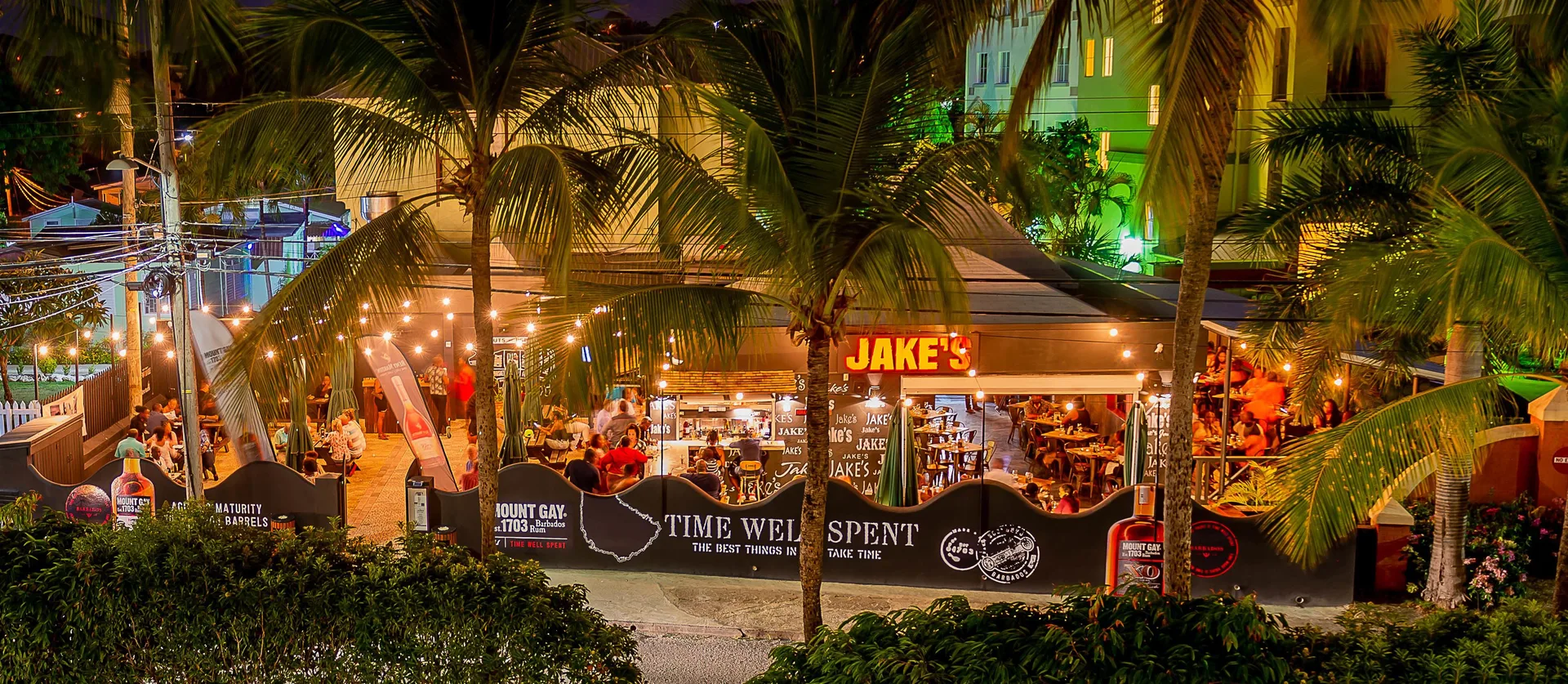Jake's restaurant exterior at night with palm trees and diners at Coconut Court Beach Hotel.