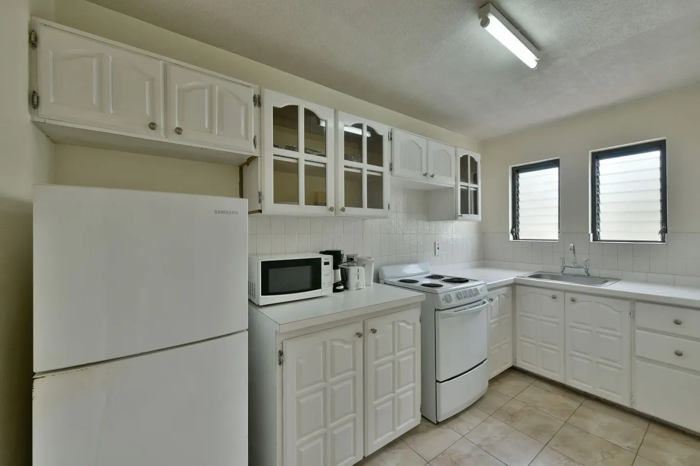 Apartment kitchen with refrigerator, stove, sink and microwave at Coconut Court Beach Hotel.