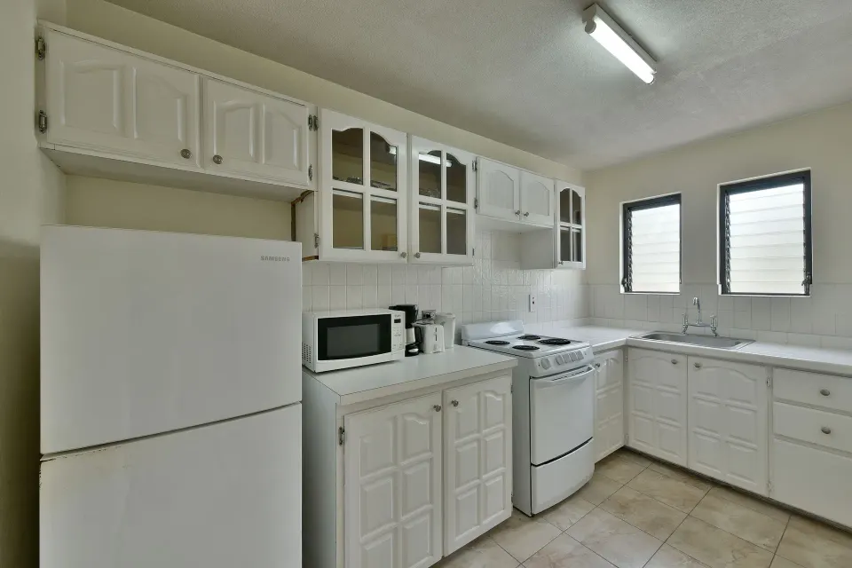 Apartment kitchen with refrigerator, stove, sink and microwave at Coconut Court Beach Hotel.