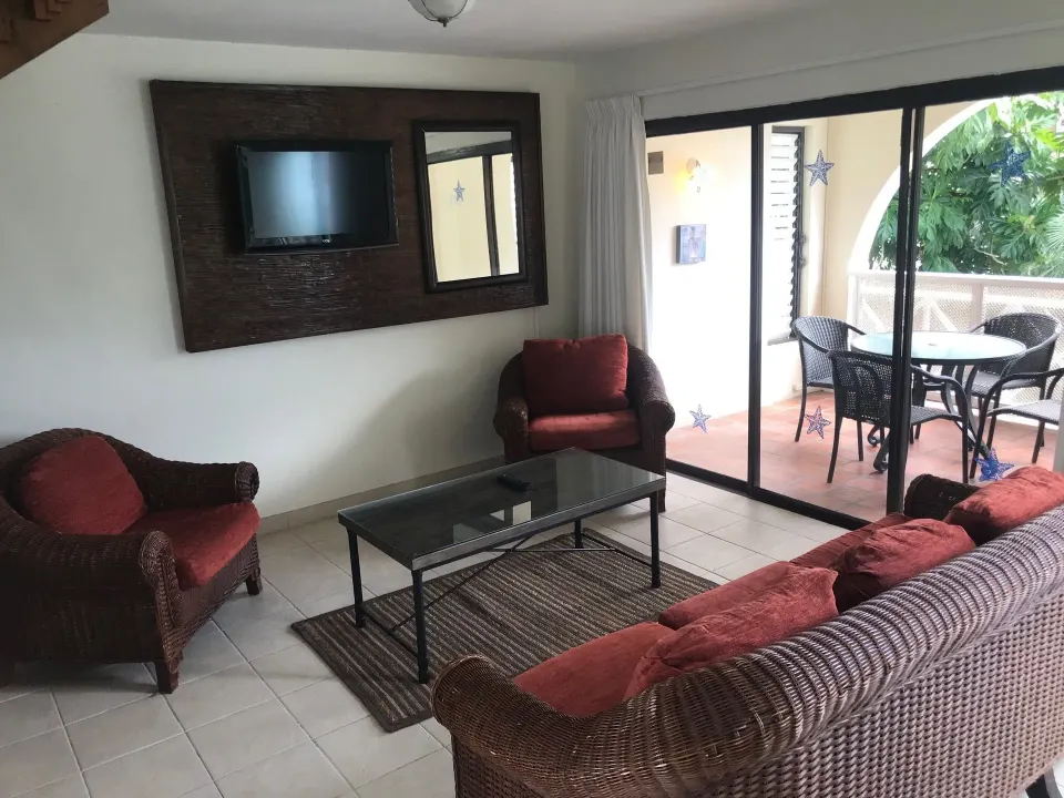 Living room opening to a furnished patio at Coconut Court Beach Hotel.