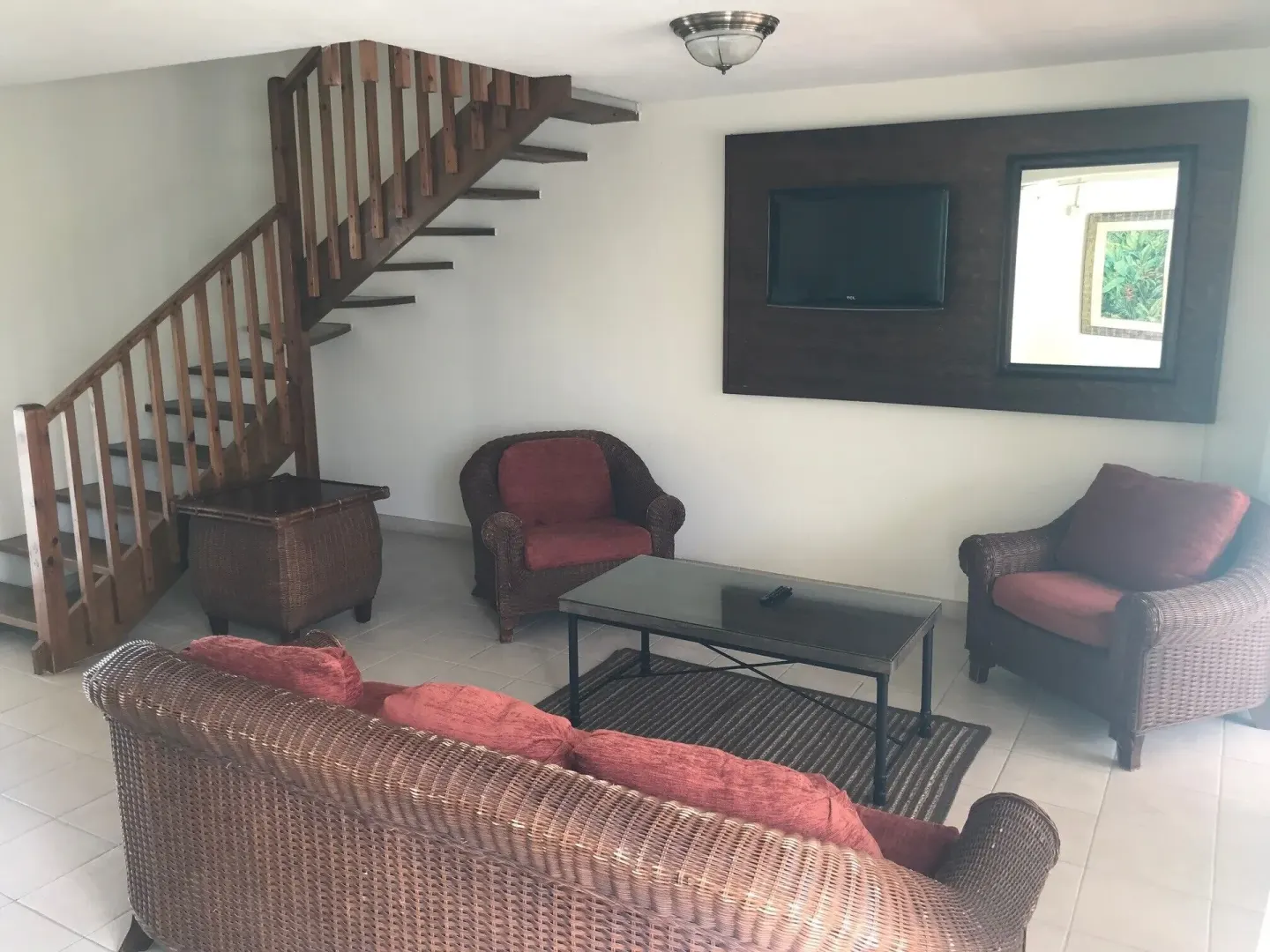 Living room with wicker seating and staircase in the apartment at Coconut Court Beach Hotel.