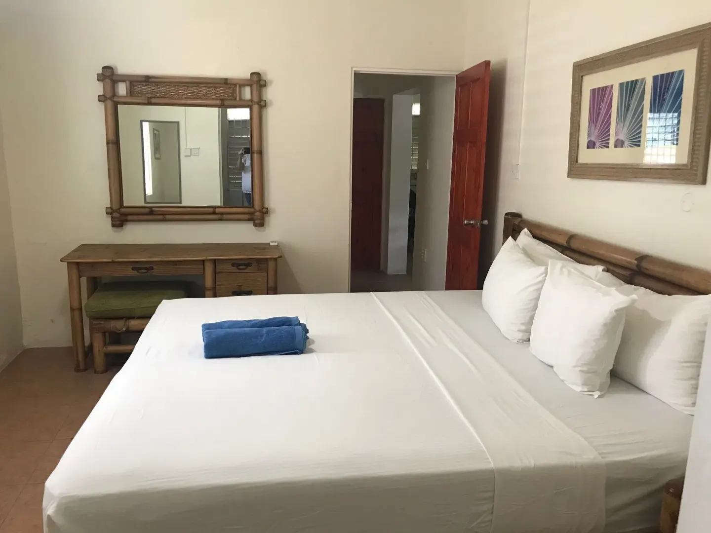 King bed, bamboo-style dresser and mirror in the apartment at Coconut Court Beach Hotel.