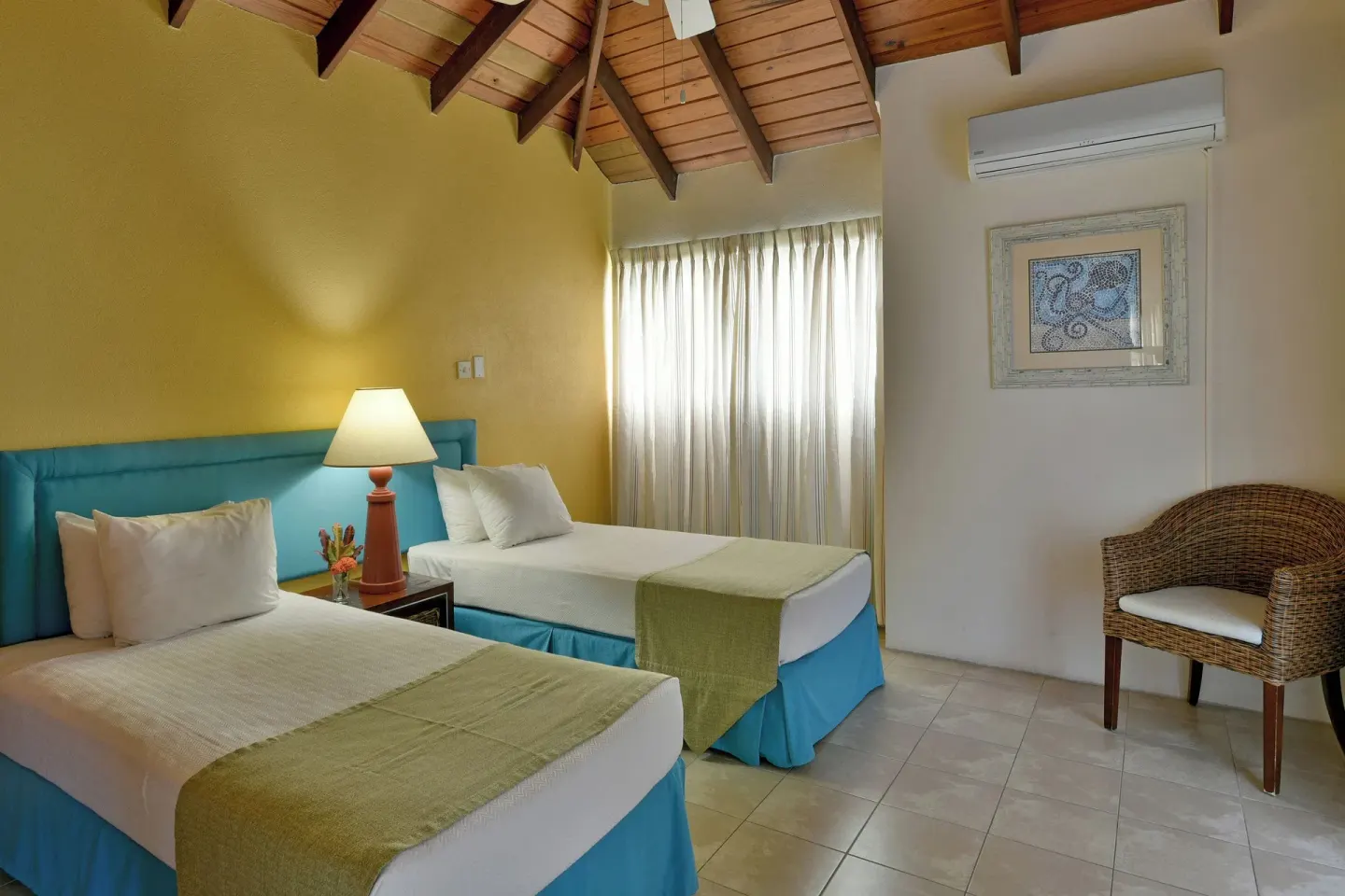 Twin beds with turquoise headboards and vaulted ceiling at Coconut Court Beach Hotel.
