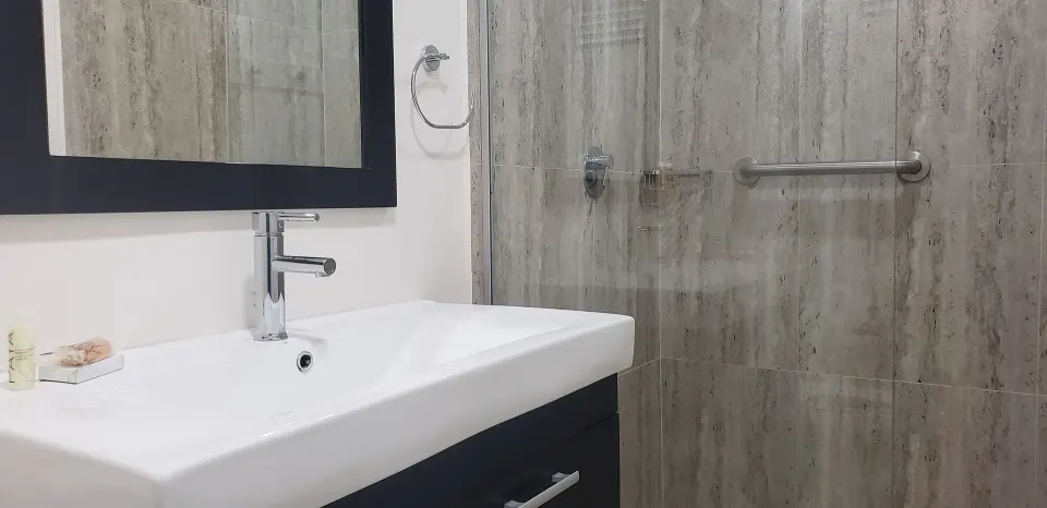 Partial Ocean View room bathroom with vanity and shower at Coconut Court Beach Hotel.