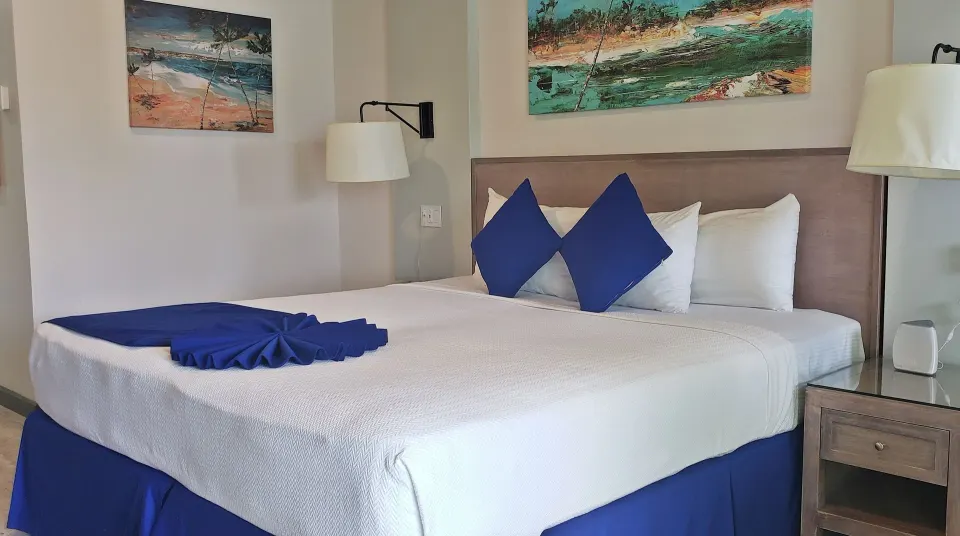 Partial Ocean View room king bed with blue pillows at Coconut Court Beach Hotel.