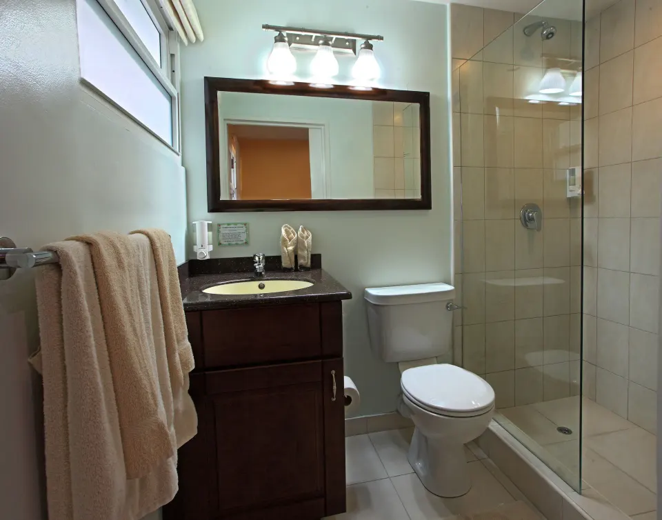 Superior Oceanfront bathroom with vanity, toilet, and glass shower at Coconut Court Beach Hotel.