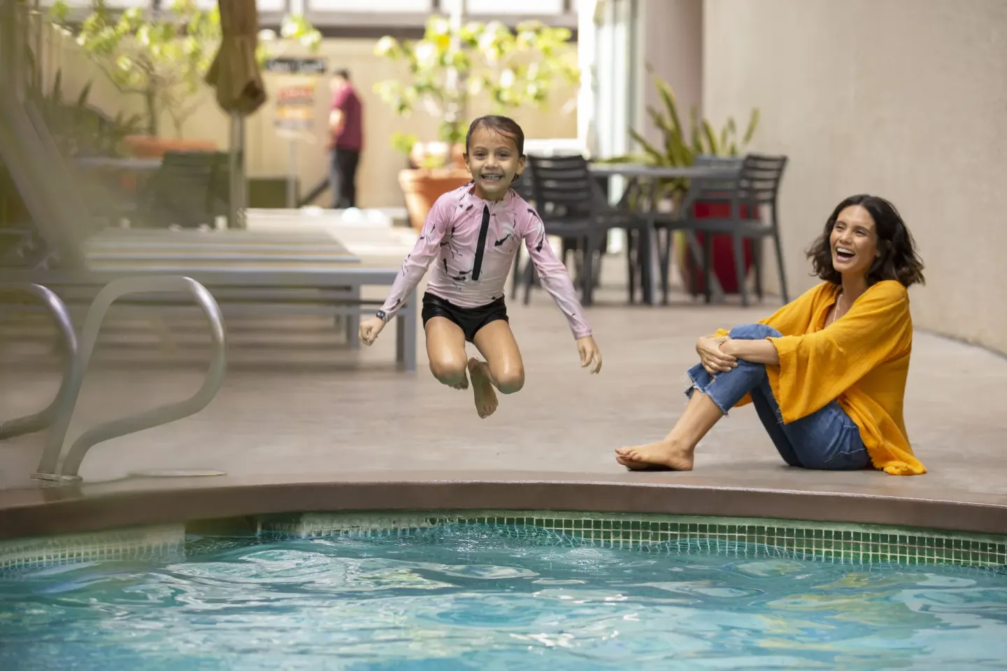 Child jumping into the pool while an adult watches at Coconut Waikiki Hotel.