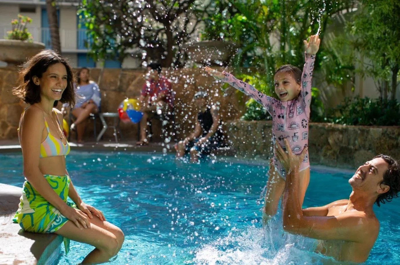 Family playing in the outdoor pool at Coconut Waikiki Hotel.
