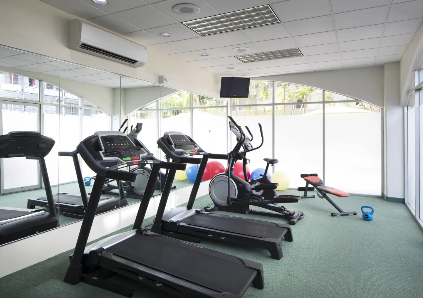 Fitness room with treadmills, bike, bench, and kettlebell at Coconut Waikiki Hotel.