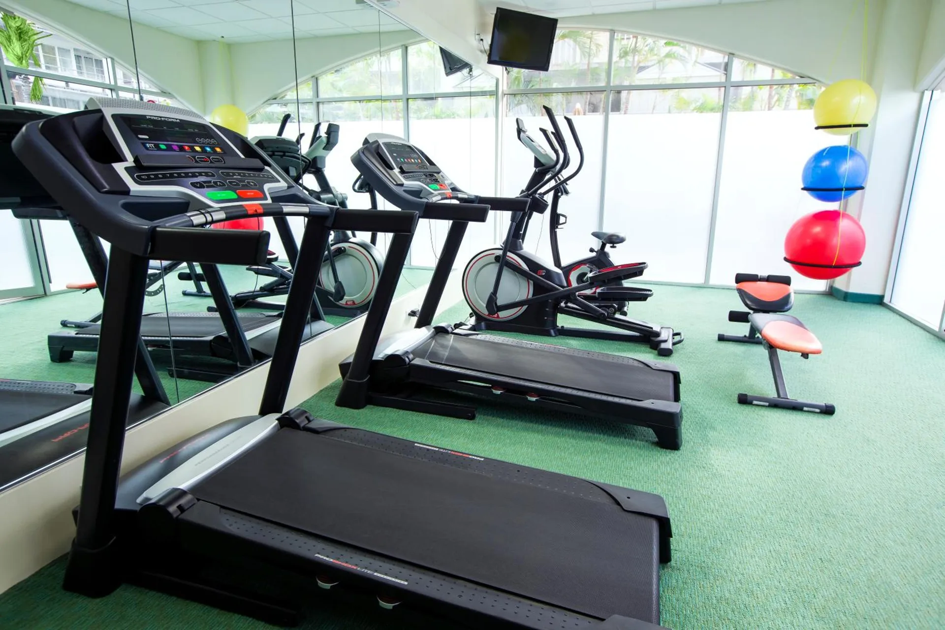 Fitness room with treadmills, bike, bench, and exercise balls at Coconut Waikiki Hotel.