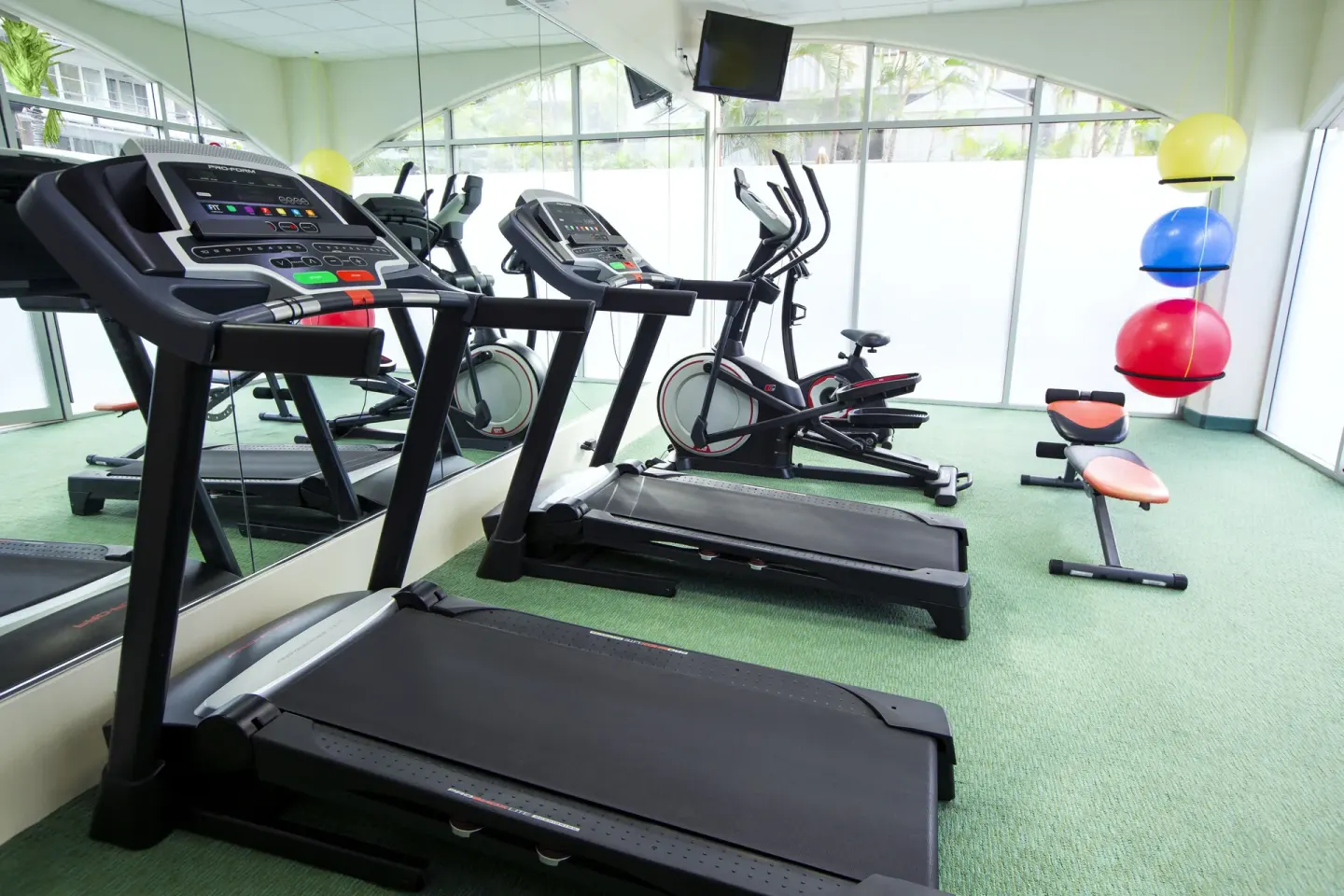 Fitness room with treadmills, bikes, and exercise balls at Coconut Waikiki Hotel.