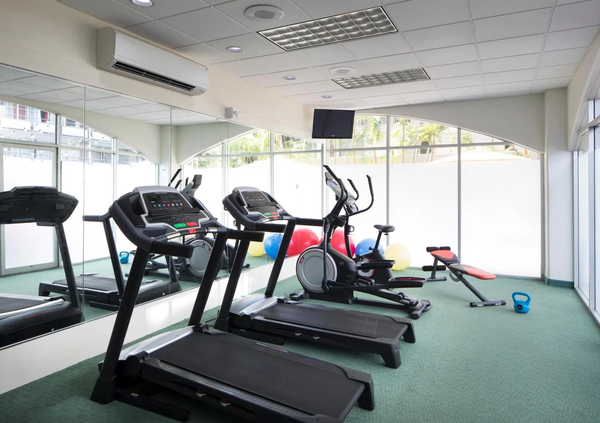 Fitness room with treadmills, bike, exercise balls, and kettlebell at Coconut Waikiki Hotel.