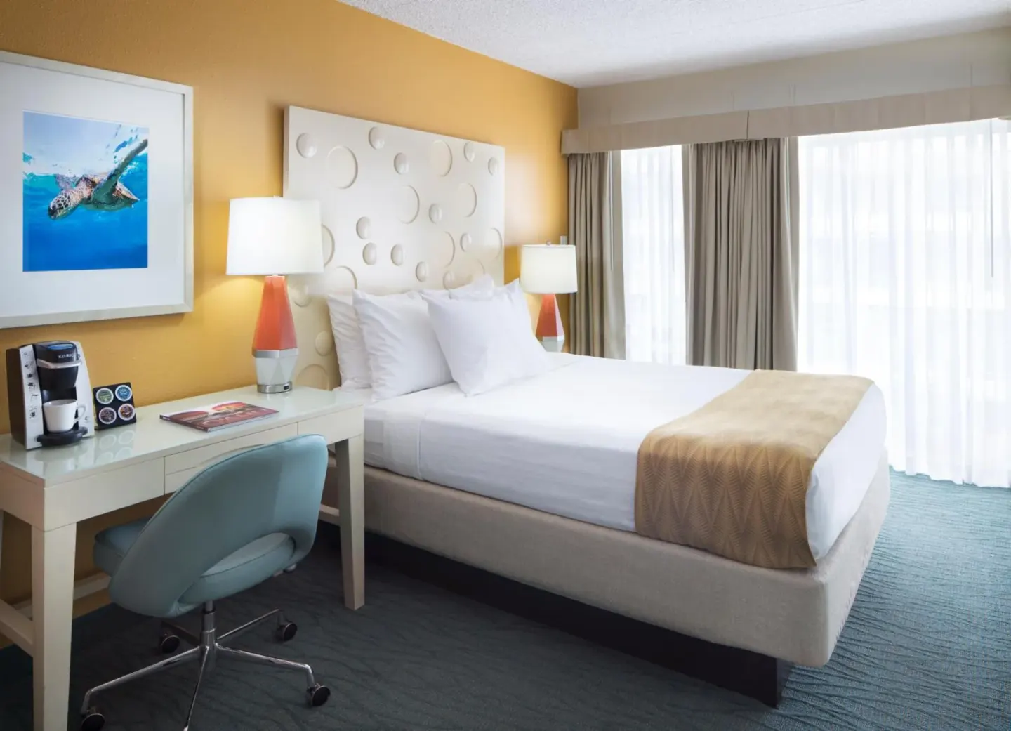 Guest room with one bed, desk, and large window at Coconut Waikiki Hotel.