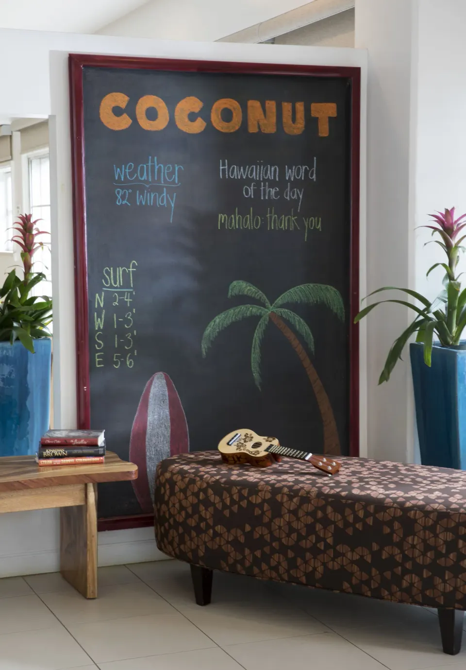 Chalkboard with weather notes and ukulele in the lobby at Coconut Waikiki Hotel.