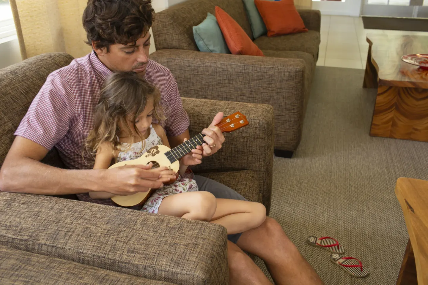 Adult and child playing ukulele in the lobby lounge at Coconut Waikiki Hotel.