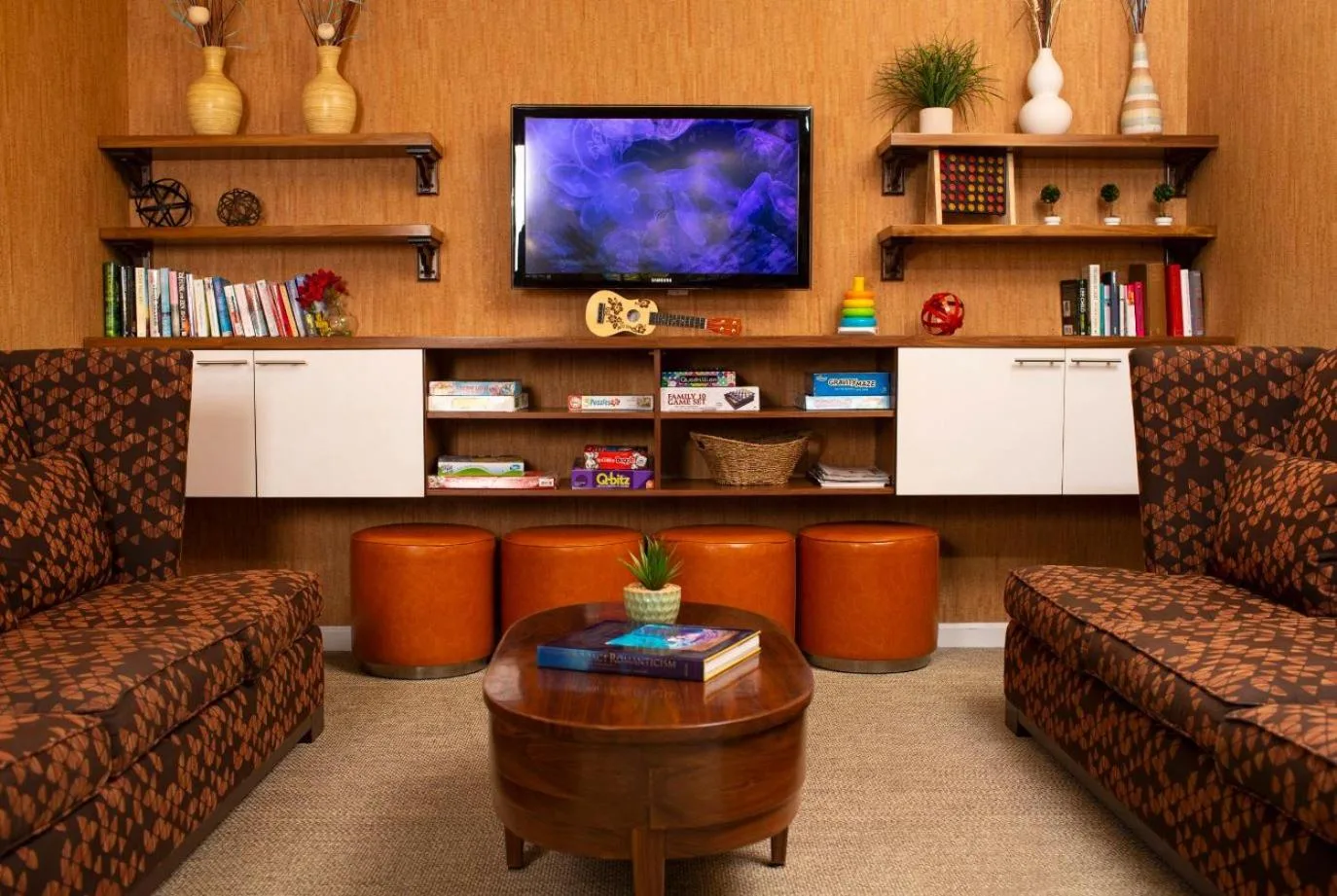 Lounge nook with sofas, TV, books, and games at Coconut Waikiki Hotel.