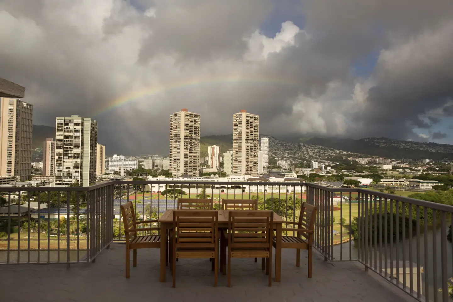 Rooftop terrace seating with city skyline and rainbow view at Coconut Waikiki Hotel.