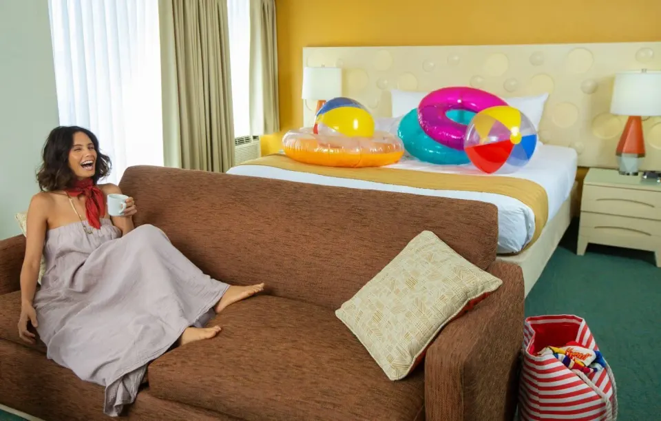 Executive Suite king bed with colorful beach inflatables and sofa at Coconut Waikiki Hotel.