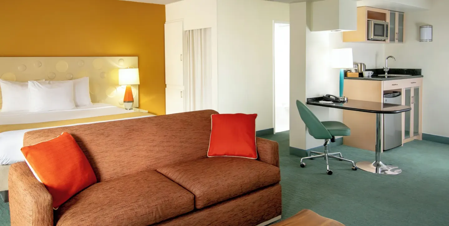 Executive Suite with king bed, sofa, kitchenette, and work table at Coconut Waikiki Hotel.