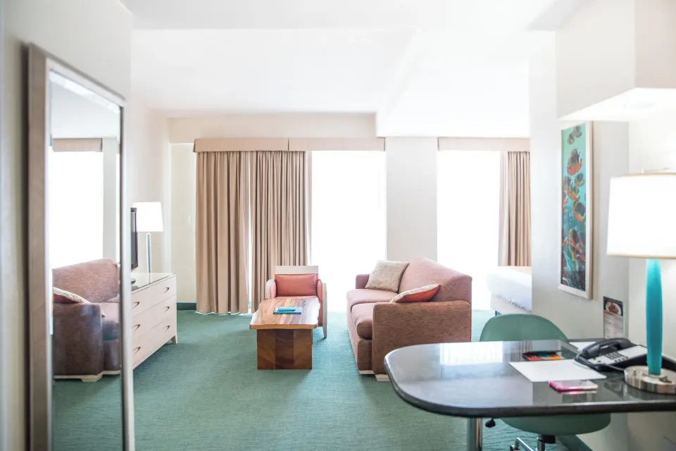Executive Suite lounge with sofa, desk, TV, coffee table, and partial bed at Coconut Waikiki Hotel.