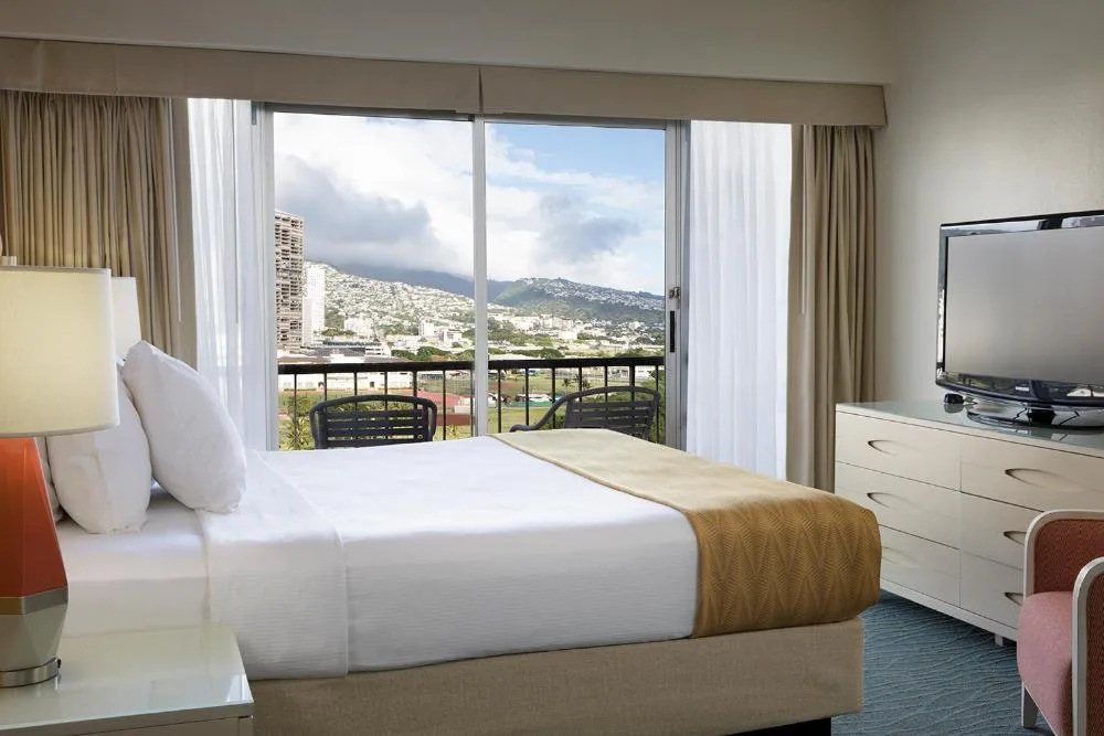 Mountain View Room at Coconut Waikiki Hotel with a king bed, TV dresser, and balcony facing the hills.