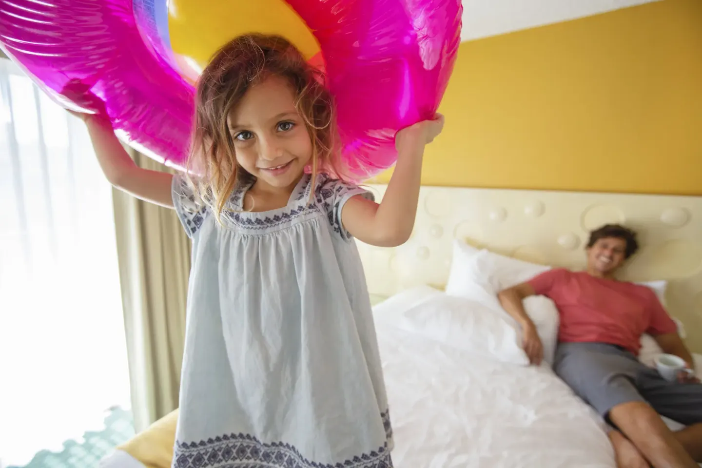 Child holding a pink inflatable in a Standard Room City View at Coconut Waikiki Hotel.