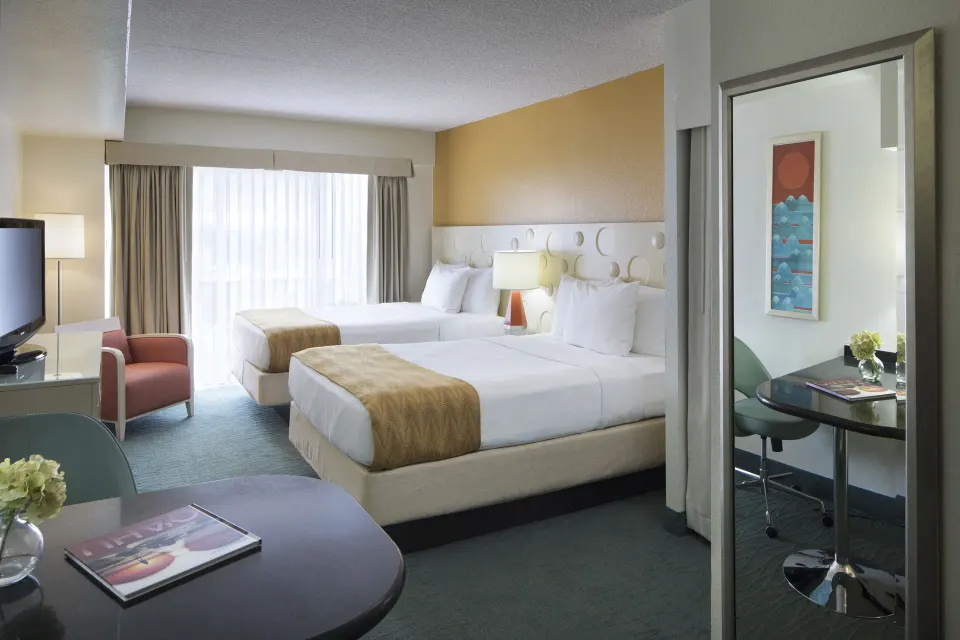 Standard Room City View with two beds, seating, and mirrored desk at Coconut Waikiki Hotel.
