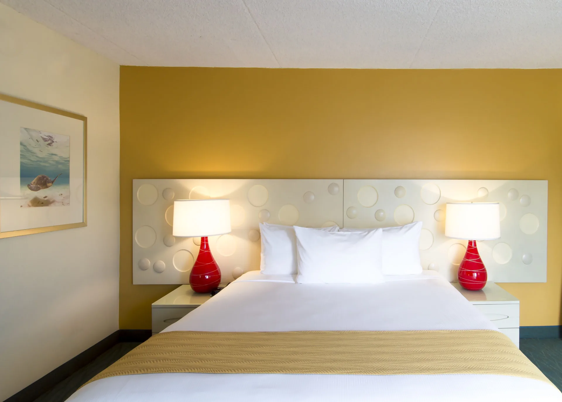 Standard Room Mountain View king bed with red lamps at Coconut Waikiki Hotel.