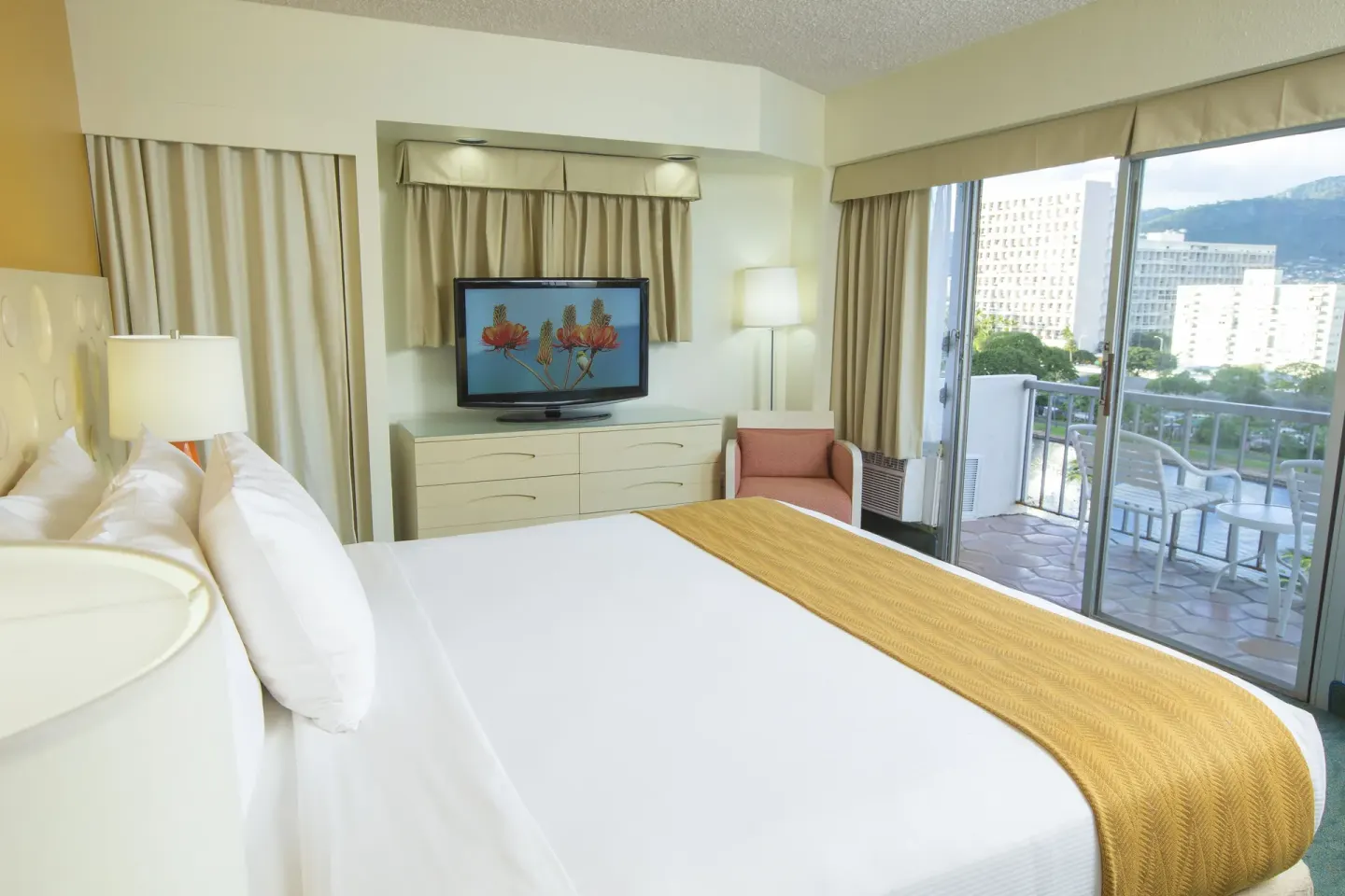Standard Room Mountain View king bed with TV and balcony at Coconut Waikiki Hotel.