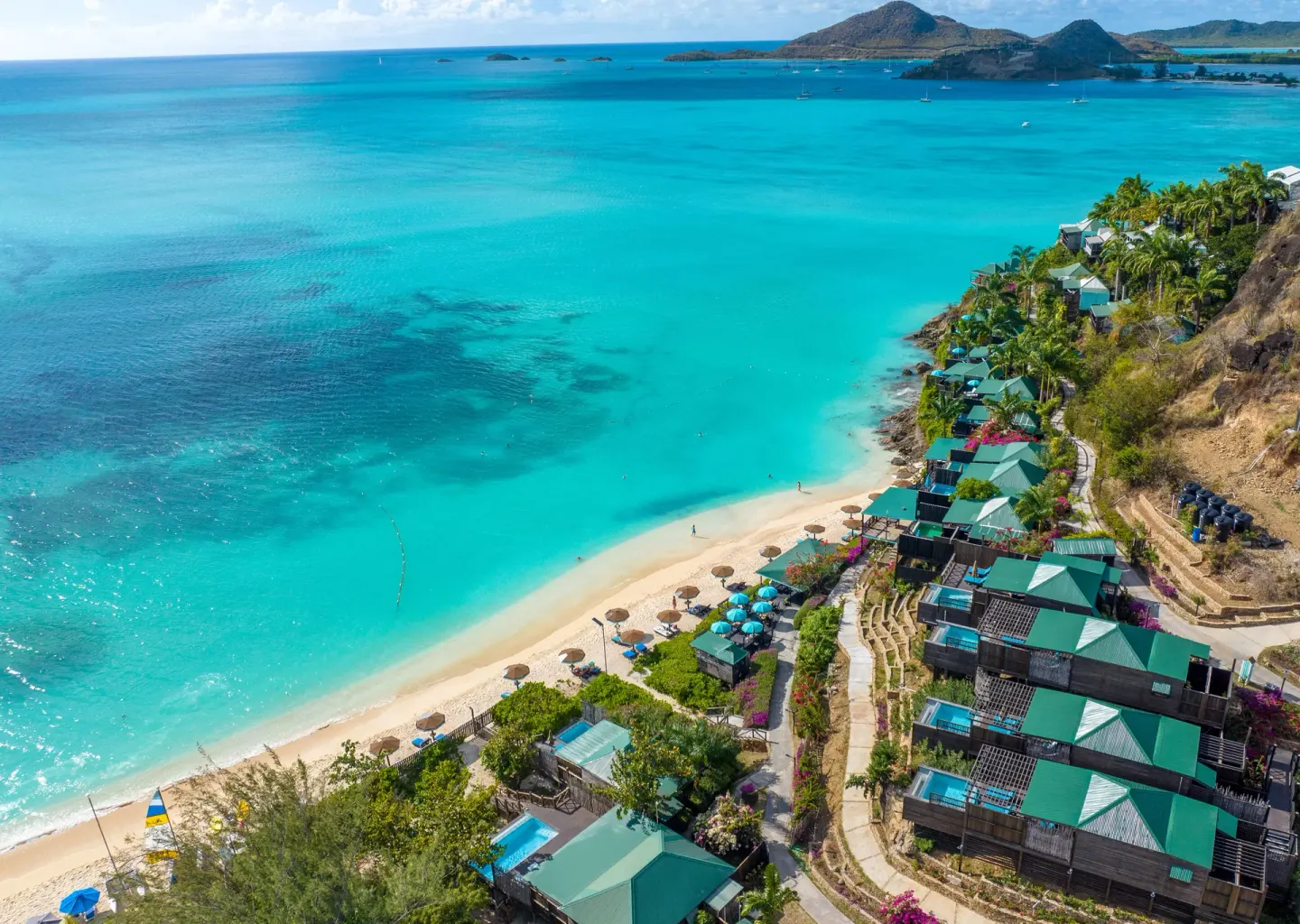 Aerial view of COCOS Hotel cottages above a turquoise bay and beach.