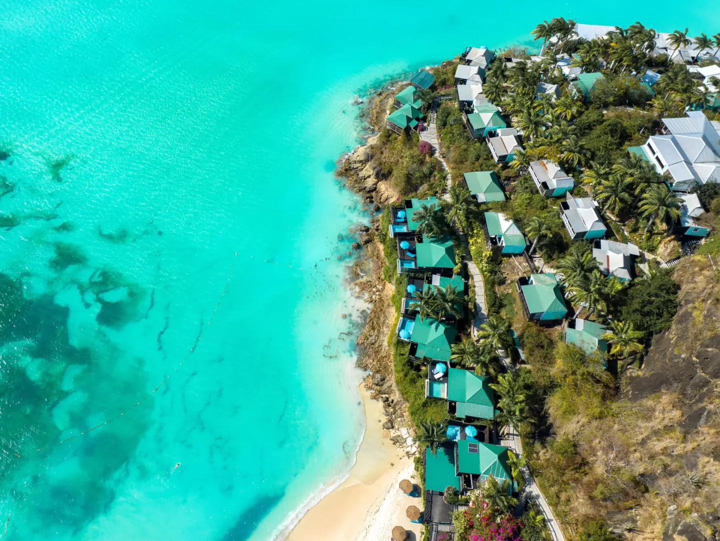 Aerial view of turquoise water and hillside cottages at COCOS Hotel.