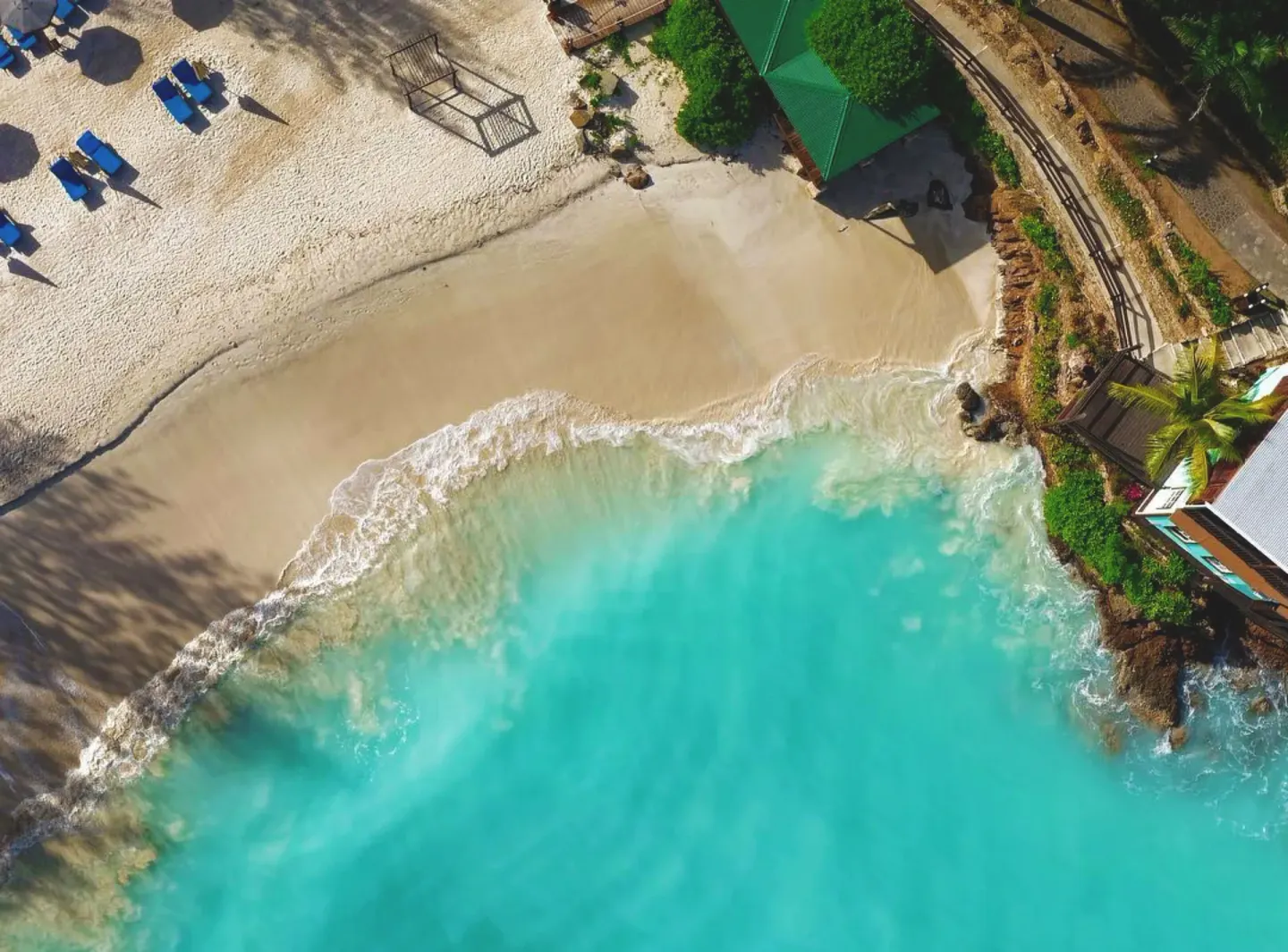 Aerial view of a small cove with turquoise surf at COCOS Hotel.