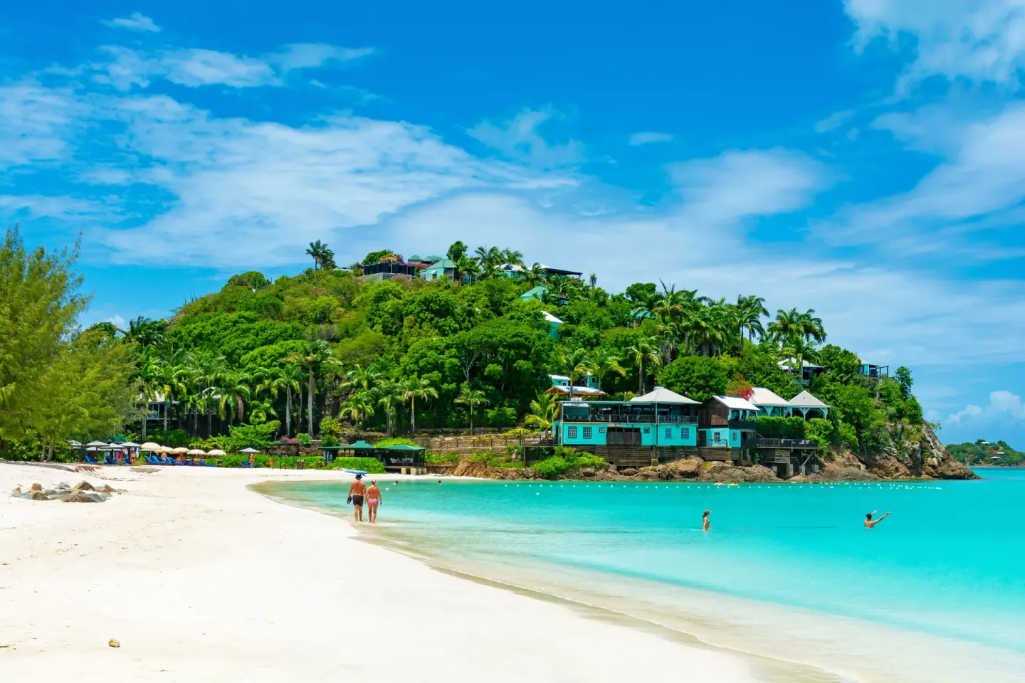 Beach and hillside resort buildings beside turquoise water at COCOS Hotel.