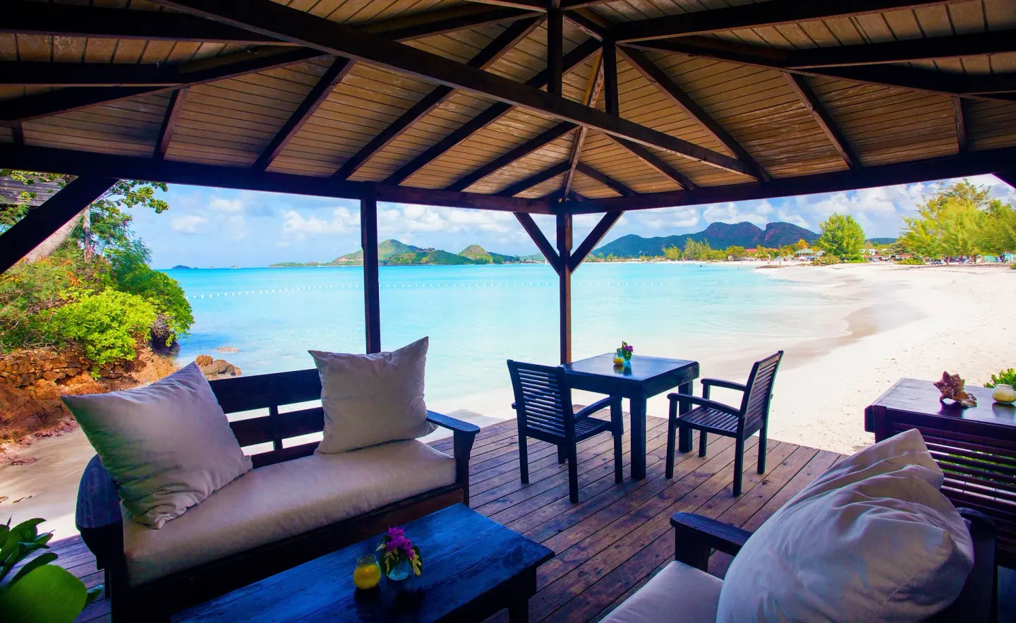 Covered beachfront lounge with sofas and a table at COCOS Hotel.