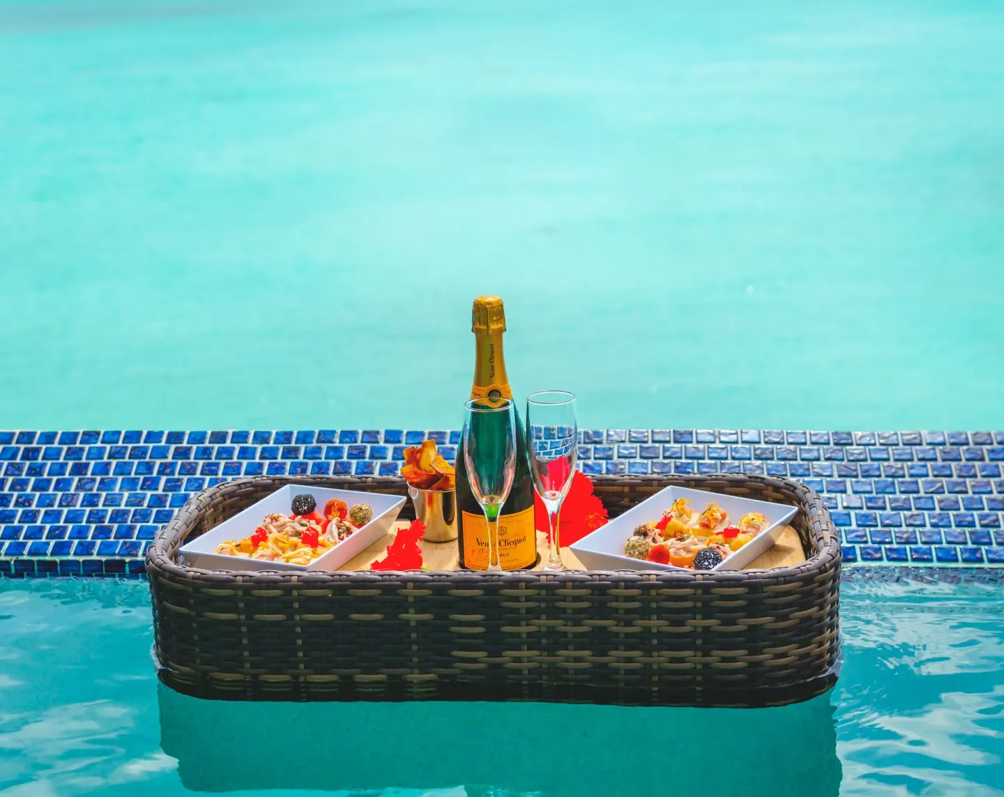 Floating tray with breakfast plates and sparkling wine in a pool at COCOS Hotel.