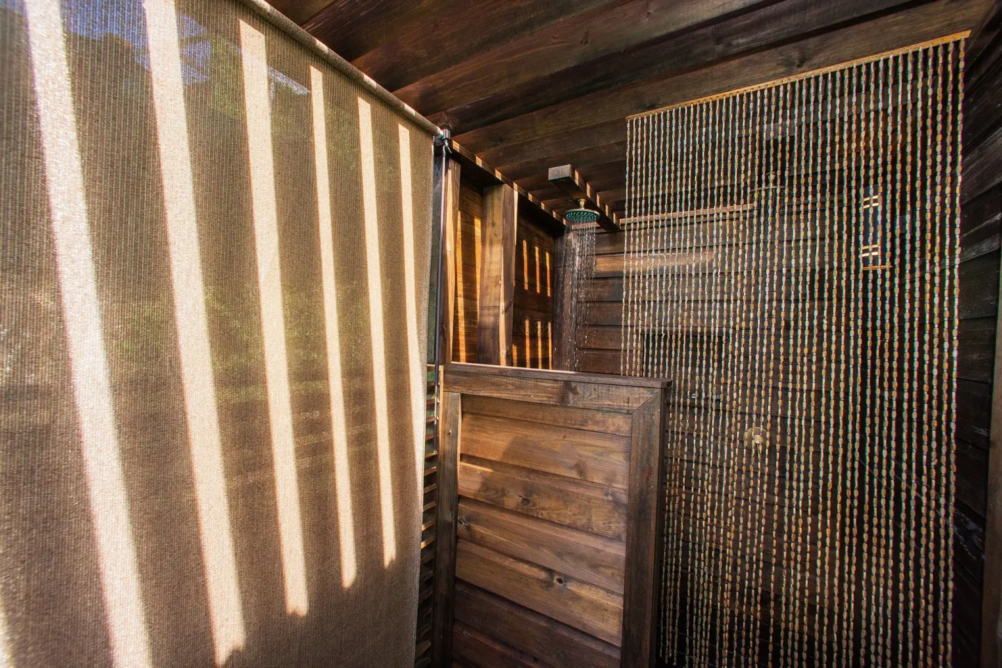 An outdoor wooden shower with privacy screens is shown at COCOS Hotel.