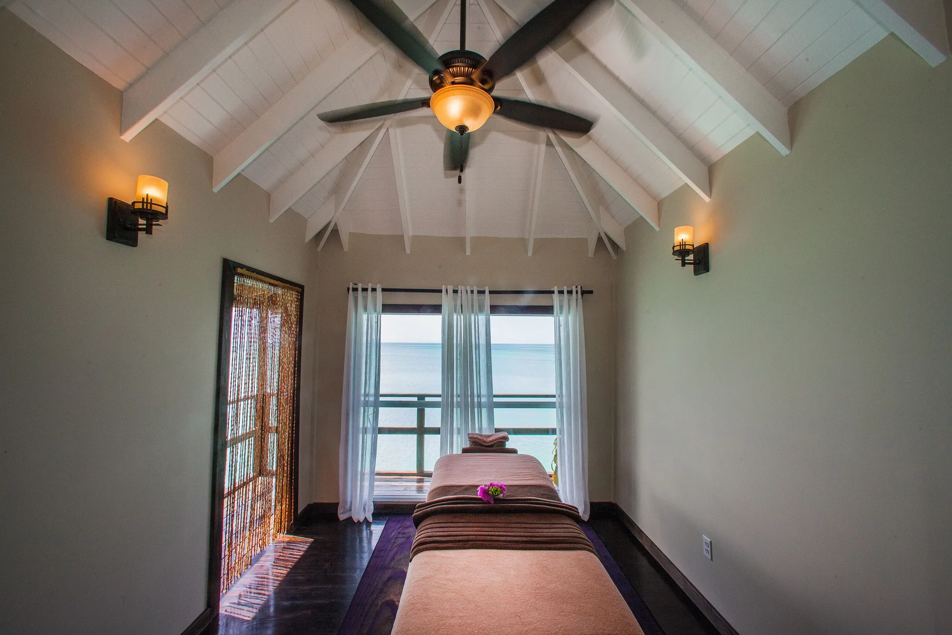 A single spa treatment bed sits beneath a vaulted ceiling at COCOS Hotel.