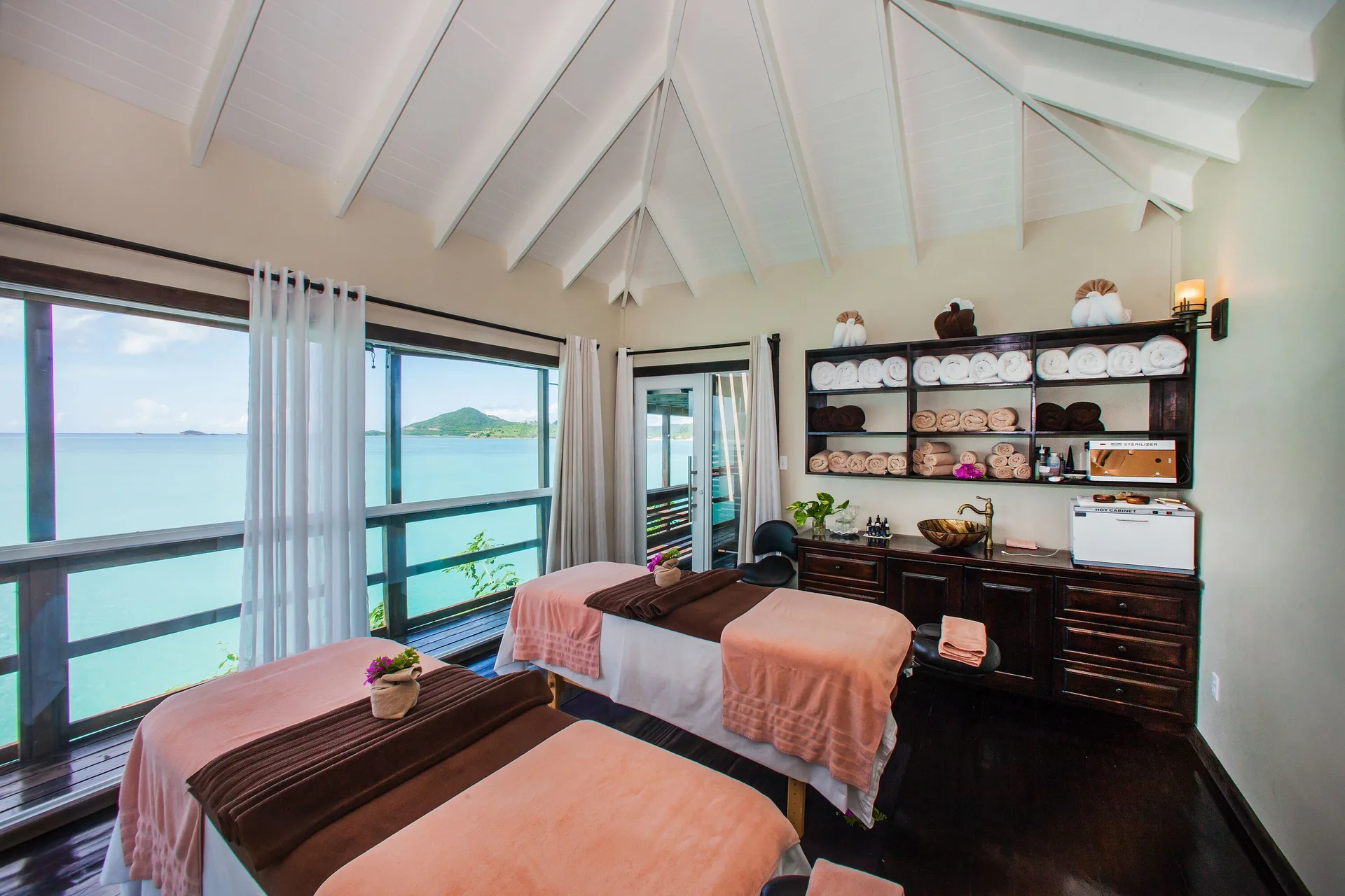 Twin spa treatment beds face the sea inside the spa at COCOS Hotel.